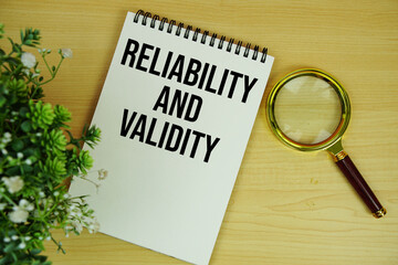 Reliability and Validity text written on notepad with magnifying glass flat lay on wooden background