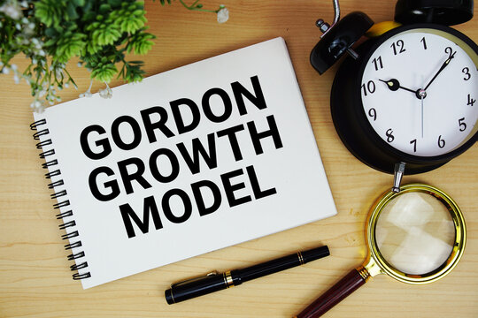 Gordon Growth Model text written on notepad with alarm clock and magnifying glass flat lay on wooden background
