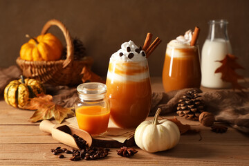 Glass of orange pumpkin spice latte and ingredients on wooden table