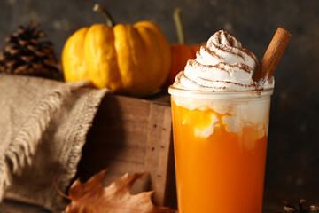 Glass of orange pumpkin spice latte on black grunge background, closeup