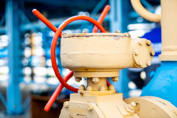 The photo shows yellow and blue gas pipes with a large red valve that shuts off the gas flow in the pipes supplying gas to homes.