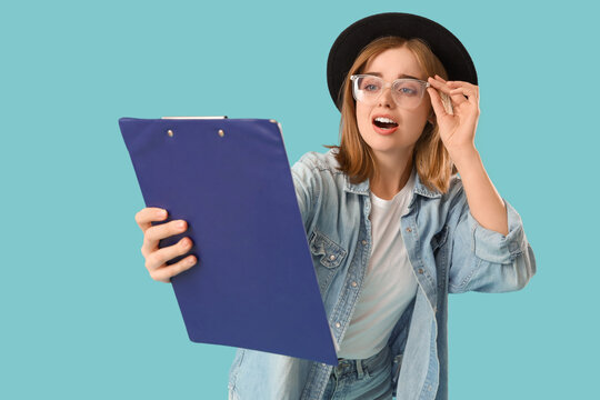 Young actress reading film script on blue background