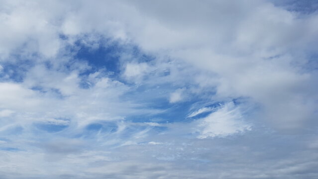 Expansive blue sky with scattered white cumulus and cirrus clouds on a clear and bright summer morning
