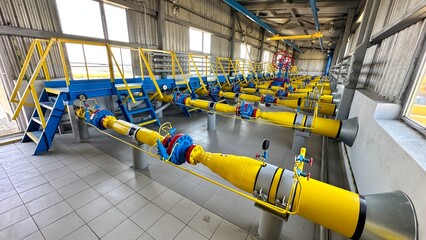 The photo shows yellow and blue gas pipes located in a large hangar. The pipes are made of...