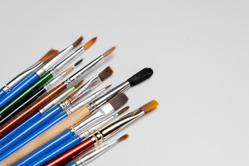 collection of art brushes of different sizes displayed on a white table. Overhead horizontal photo. Craft hobby background. Recomforting, destressing hobby, art therapy
