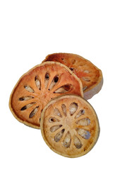 Three dried bael fruit slices rest in a graceful row against a translucent background, their intricate patterns glowing like natural mandalas. The composition highlights the quiet beauty of traditiona