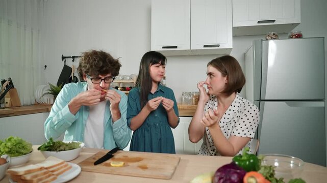 Happy caucasian father and mother sitting and eating fruit at modern kitchen. Energetic family spend time together by enjoy eating fruit or healthy fruit with kitchenware and fruit on table. Pedagogy.