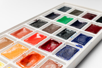 set of watercolor paints on a white background. Unleash your inner artist. A colorful set of watercolor paints and drawing paper is a great tool for developing your imagination and creativity