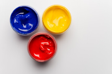 Jars of multi-colored gouache on a white background. Blue, red, and yellow traffic light colors.