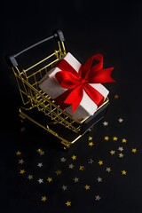 Golden Shopping Cart with Gift Box and Star Confetti on Dark Holiday Background