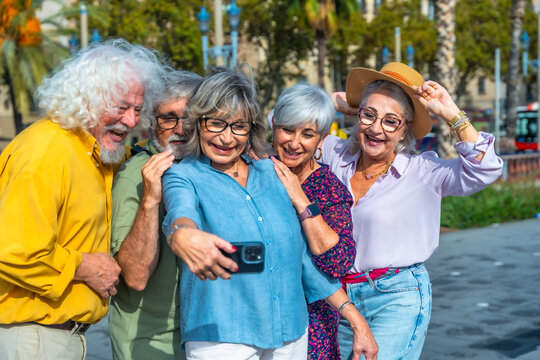 Seniors friends taking happy selfie using smartphone outdoors