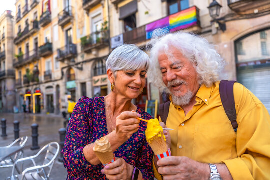 Senior couple sharing ice cream cone on city street
