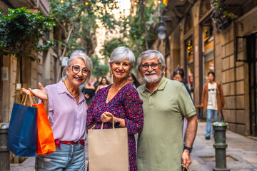 Cheerful seniors friends enjoying shopping on city street