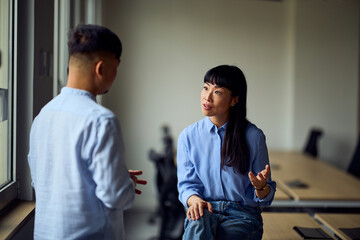 Asian Woman And Asian Man In A Modern Office Having A Professional Conversation