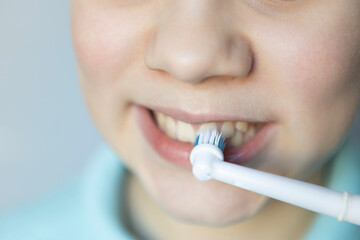 Child brushing teeth with an electric toothbrush in a bright, clean bathroom during morning routine