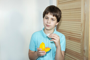 Boy holds yellow toy while looking thoughtful in a brightly lit room with wooden decor