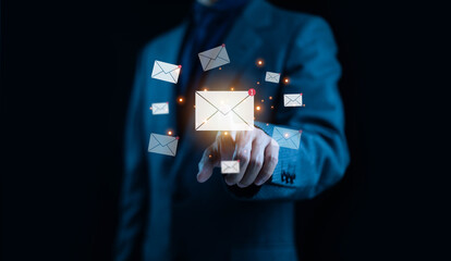 Businessman touching a glowing email icon with multiple message notifications symbolizing digital communication email marketing, online messaging, customer interaction, and modern business technology.