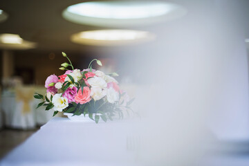 Beautiful floral arrangement on a table during a wedding reception in a bright banquet hall surrounded by elegant decor and warm lighting