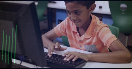 Typing boy in orange-striped polo leaning in school computer lab, using black keyboard and monitor