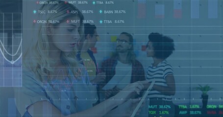 Tapping tablet, woman in blue top at office, team reading papers, sticky notes, charts, copy space