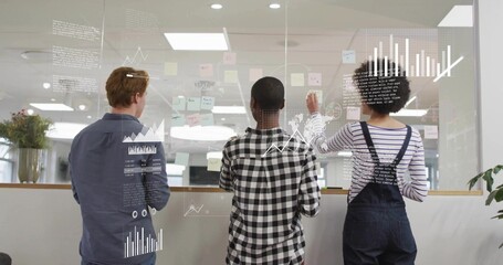 Planning team wearing casual attire placing post-its on glass board with digital graphs at office