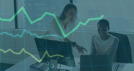 Pointing two women working in office in blazers, using laptop and screen with green-yellow chart