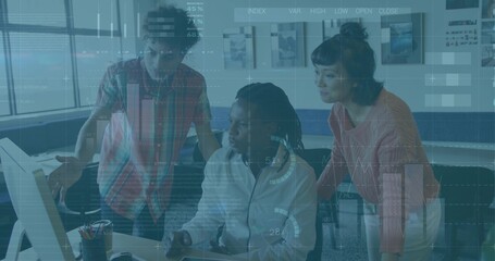 Reviewing team wearing salmon, plaid, zip tops, leaning over office computer showing charts