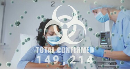 Sitting patient masked and reclining in hospital ward, nurse in scrubs checking IV pump, biohazard