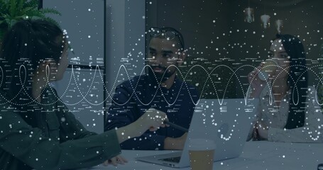 Listening midage male in dark top leaning to coworker at conference table, with laptop data overlay