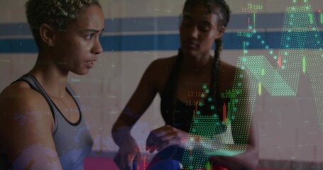 Balancing blue ball, two women in sports tops training in gym with candlestick overlays, pink mat