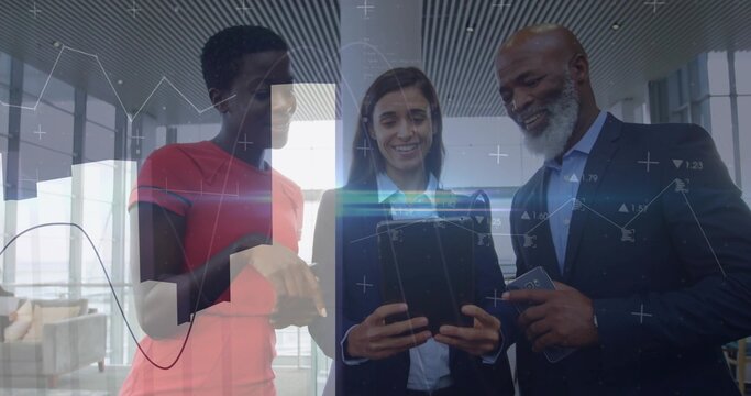 Three colleagues discussing data overlays in lobby, pointing at tablet and phone, suits red tee