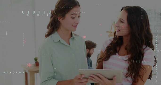Discussing two colleagues in mint shirt and pink top holding tablet at office, binary overlay