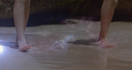 Naklejka premium Wading two kids' bare feet in shallow shoreline water at beach, showing footprints and lens flare