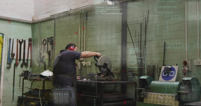 Positioning man wearing apron and red muffs, cutting metal bar at workshop bench with chop saw