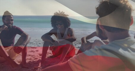 Naklejka premium Chatting five adults sitting on sand by ocean, with sunglasses, casual beachwear and flag overlay