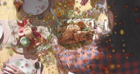 Placing host in red-blue plaid shirt arranging roasted whole bird on home table, with candles