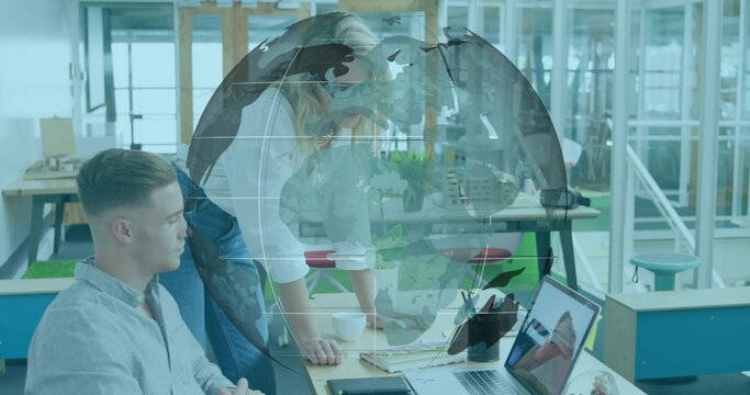Leaning colleagues in business casual clothes reviewing laptop at open office, with globe overlay