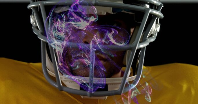 Facing camera male football player wearing helmet and yellow jersey in studio, showing purple smoke - Powered by Adobe