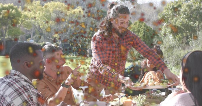 Serving man in red plaid shirt handing roasted chicken platter at garden table, with wine glasses
