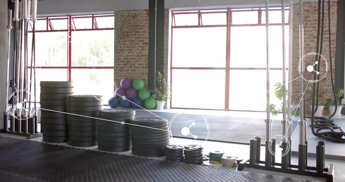 Stacking black bumper plates occupying left-of-center on rubber floor, with colorful balls