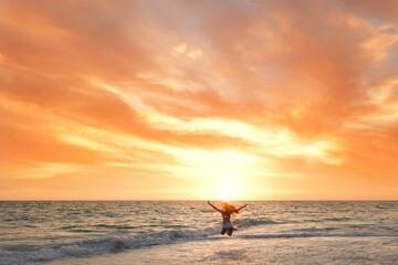 Young girl jumping on beach beautiful sunset Anna Maria Island