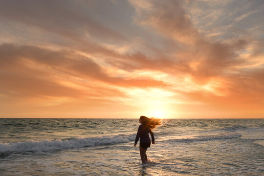 Behind teenage girl flipping hair on beach beautiful sunset Gulf
