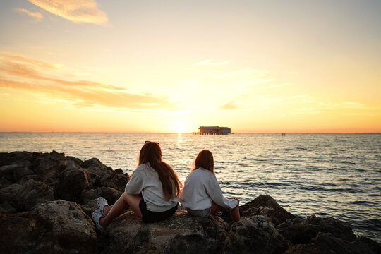 Behind teen sisters watching beautiful sunrise Anna Maria City P