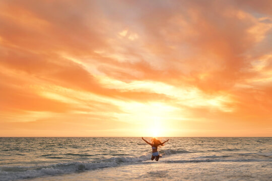 Young girl jumping on beach beautiful sunset Anna Maria Island