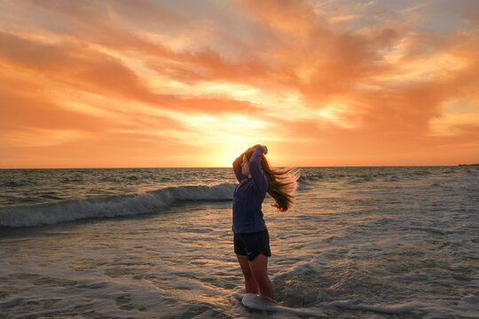 Side view beautiful teen girl flipping hair on beach sunset Anna