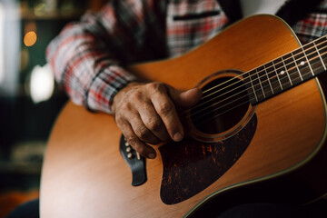 Man plays acoustic guitar in cozy indoor setting