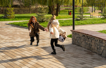 Mother and daughter walking hand-in-hand through a landscaped park in cool weather. Autumn vibes, warm clothes, peaceful moment.