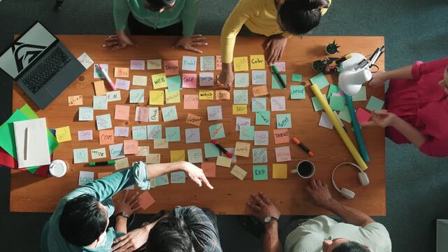 Top view of smart business team explain and discuss about project design at meeting room with laptop and sticky notes. Aerial view of designer designing logo brand design while standing. Symposium.
