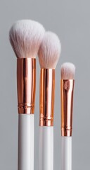 Three makeup brushes, white handles, rose gold details