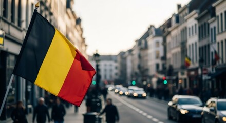 Belgian national flag waving on a city street with blurred background of cars and buildings. Patriotism and national identity concept for celebration.